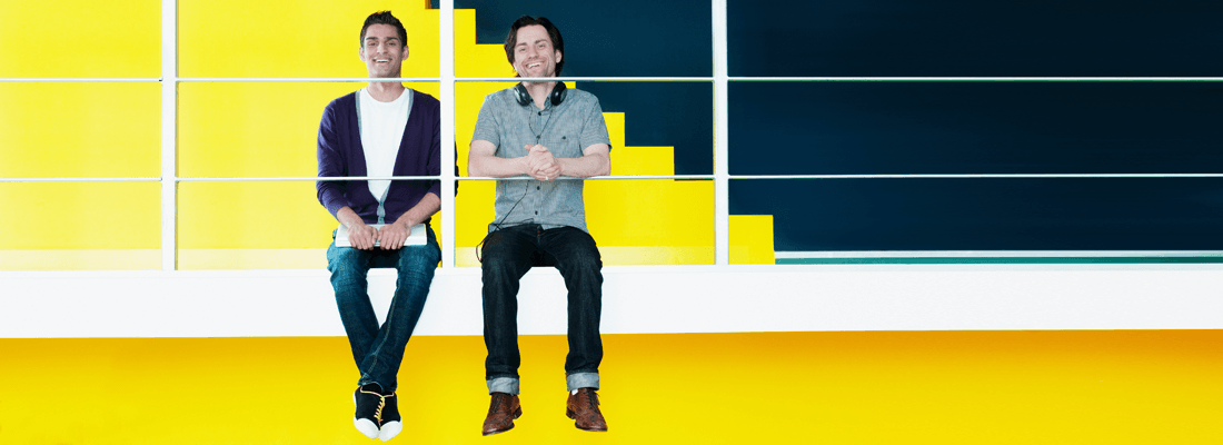Twee gelukkige mannen op kantoor tegen een gele achtergrond